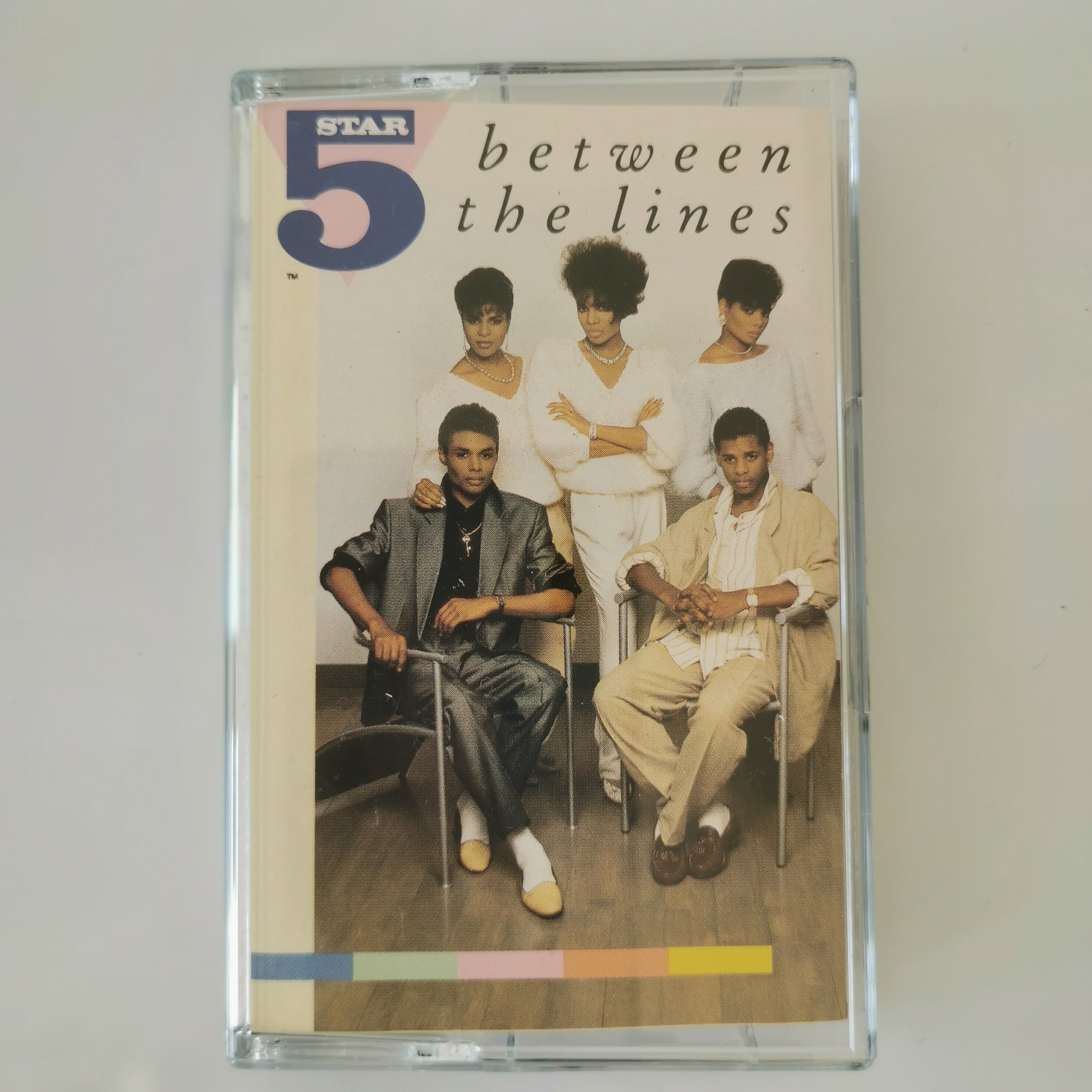 A vintage cassette tape of the band 5 'between the lines' in its clear plastic protective case, photographed against a neutral light gray background.