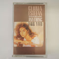 A vintage cassette tape of Gloria Estefan's 'Anything For You' in its clear plastic case, photographed against a plain light background.