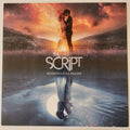 Album cover for 'The Script - Sunsets & Full Moons' featuring a dramatic sunset scene with a couple embracing, their figures dissolving into sparkles, and a reflection in water below.