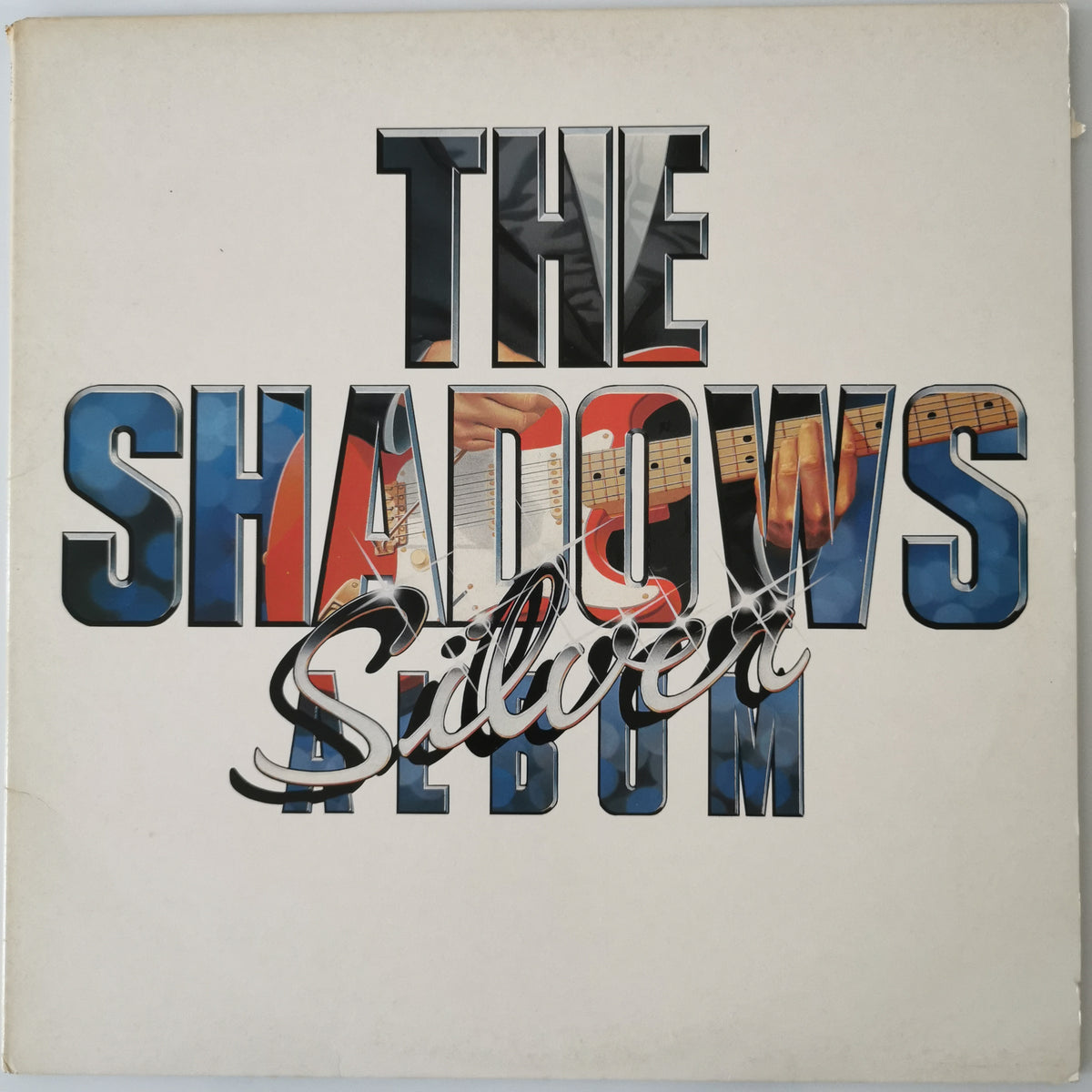 The Shadows 'Silver' album cover, featuring the band name 'THE SHADOWS' in large 3D letters with guitar imagery inside, and 'Silver' in cursive script across the front, set against a cream-colored background.