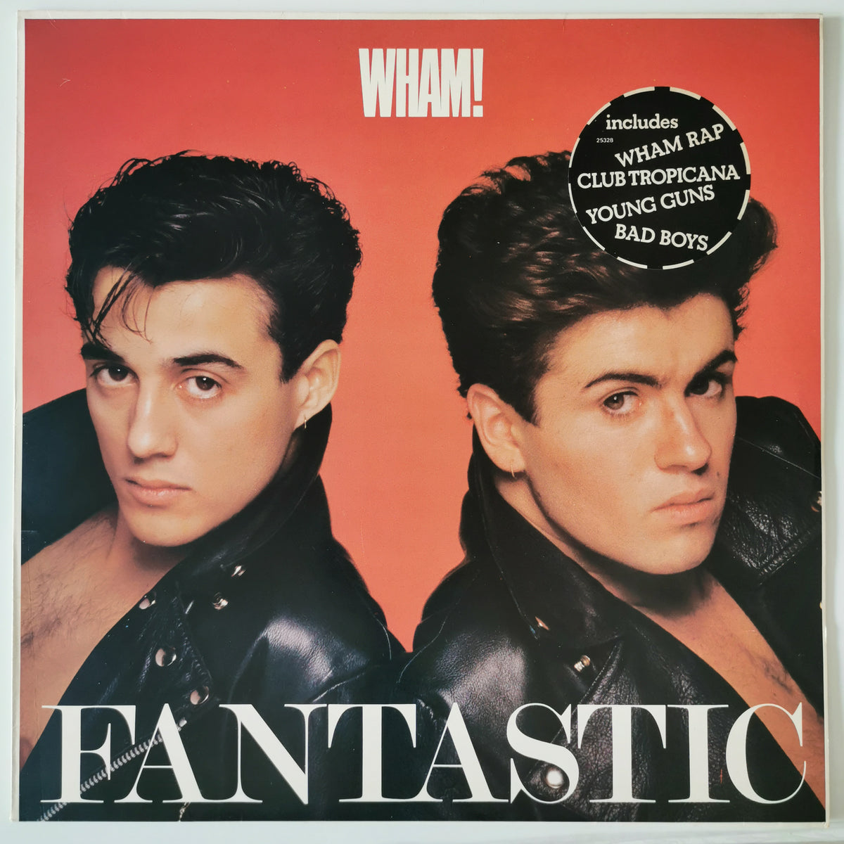 Wham! 'Fantastic' vinyl record cover featuring two men in black leather jackets against a red-orange background, with white title text and a black circular sticker listing included tracks.